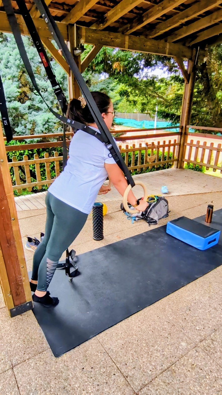 S&eacute;ance de coaching sportif en ext&eacute;rieur : exercice de tirage aux anneaux avec sangles de suspension